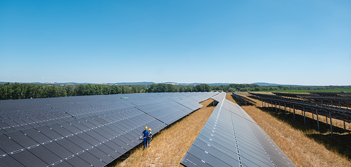 Large scale photovoltaic power plant with people standing at the panels