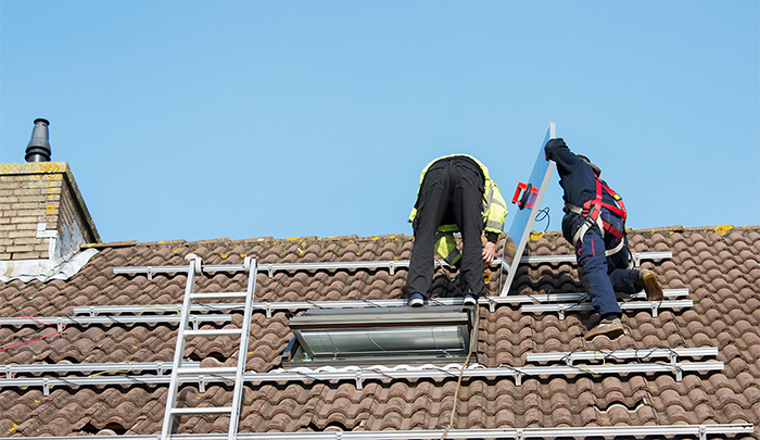 man putting the solar panel to the metal construction on the roof