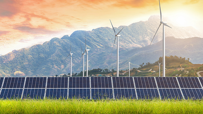 Asphalt road with solar panels with wind turbines against mountanis landscape against sunset sky,Alternative energy concept