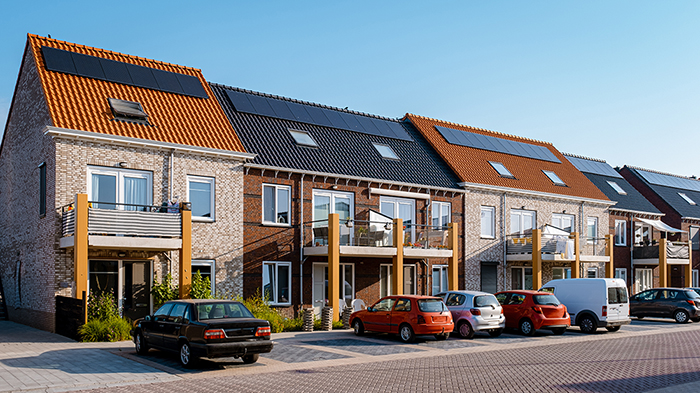 Newly build houses with solar panels attached on the roof against a sunny sky Close up of a new building with black solar panels. Zonnepanelen, Zonne energie, Translation: Solar panel, , Sun Energy.